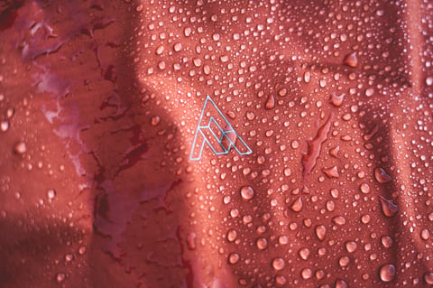 Water beads on the orange-red fabric of a 7mesh Copilot, one of the waterproof cycling jackets on test.