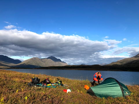 Green Wild Country Zephyros Compact 2 pitched beside a Highland loch, with a camper, a bike and kit on the grass.