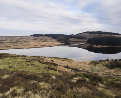 Rider on a moorland track beside a reservoir on the Glasgow Inner Circle gravel route.