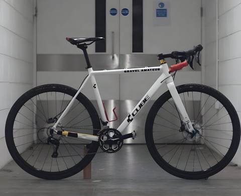 Will Jones's repainted white Cube Cross Race Pro, the Gravel Amateur, side on with red grips on the drops.