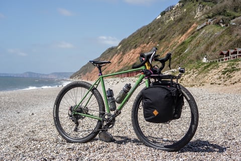 Green Fairlight Faran 2 with front rack and Restrap panniers on a pebble beach below red cliffs in East Devon.
