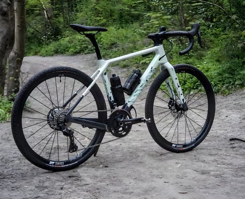 Canyon Grizl CF SL 8 gravel bike in pale green with Shimano GRX cranks, parked on a woodland trail.
