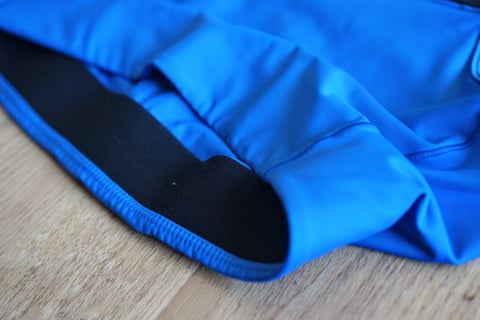 Wide black elastic underband inside the hem of the blue Foundations Sports Bra, close up.