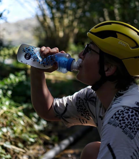 Rider in a yellow helmet drinks through the filter nozzle of a Katadyn BeFree 0.6L soft flask.