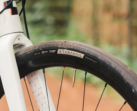 Teravail Rampart 700c x 38 Durable tyre in the fork of a white bike, its sidewall lettering and tubeless valve in close-up.