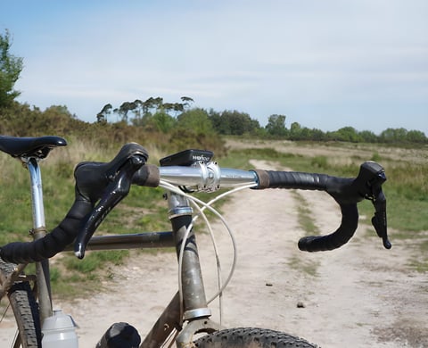 View over Salsa Cowchipper Deluxe 52cm bars with Wahoo computer, looking along a sandy gravel track in East Devon.