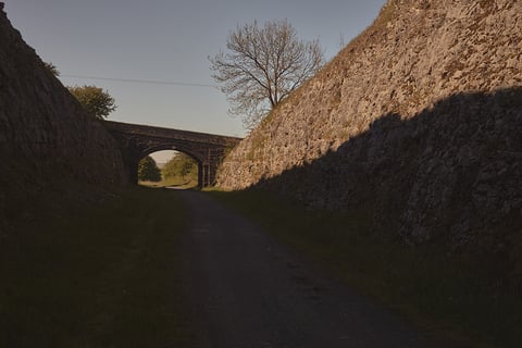 Old stone bridge over a path cut between steep rock walls on the Leeds to Lyme Regis route.