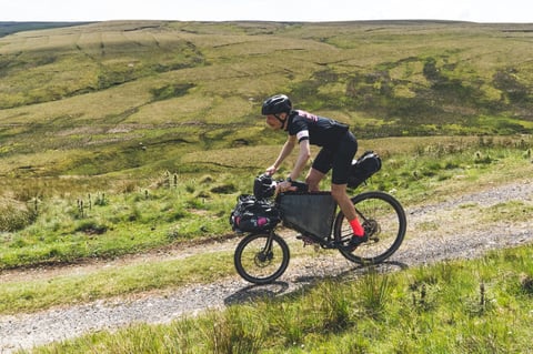 Farr Out Deliveries rider on the Rothair cargo bike grinds up a gravel track across open Pennine moorland.