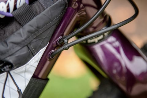 Cable ports on the down tube of the Lord Cycles Nomad beside the frame bag, in glossy purple paint.