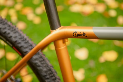Side view of the Superchub's seat cluster, where the copper top tube and seat stays meet, tyre tread below.