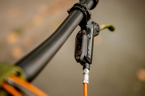 SRAM Level brake lever with a green anodised blade and orange braided hose on the Quirk Superchub.