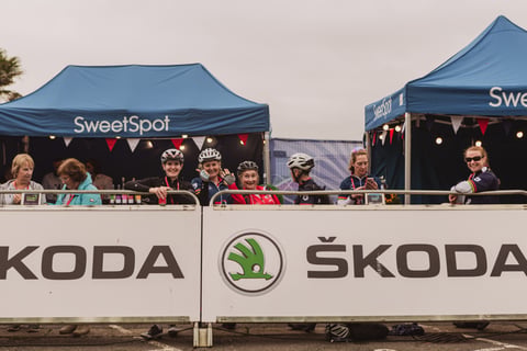 Riders and volunteers behind Škoda barriers at the SweetSpot tents in the Women's Tour of Britain finish area.