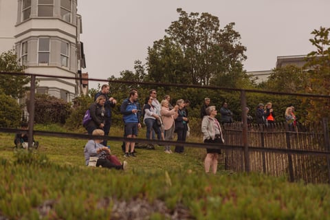 Spectators stand on a grassy bank behind railings to watch stage 4 of the Women's Tour of Britain in Southend.