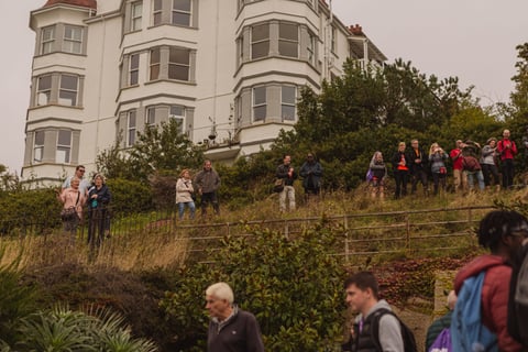 Crowds line a hillside below a white bay-windowed building to watch the Women's Tour of Britain in Southend.