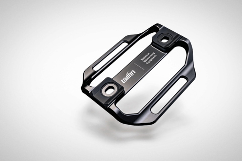 Tailfin Mini Cage in black, angled view showing the CNC-machined slots and two mounting bosses.