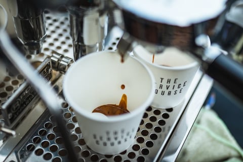 Espresso pouring from a machine into two Service Course paper cups at the Gravel Bonanza.