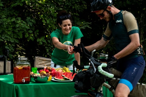 Hungarian Divide rider takes a piece of fruit at a roadside refreshment table with watermelon and homemade lemonade.