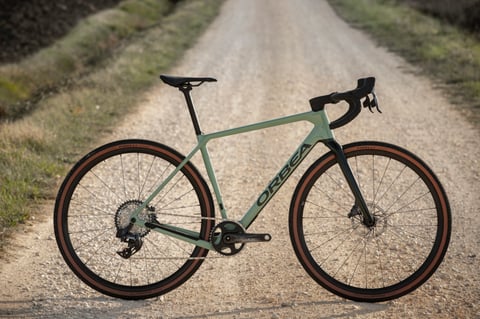 Side view of a green Orbea Terra with tan-wall Pirelli tyres on a gravel road.