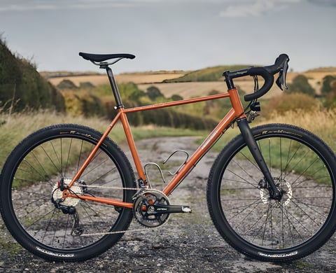 Fairlight Secan in orange with GRX cranks and Continental tyres, drive side, on a gravel track.