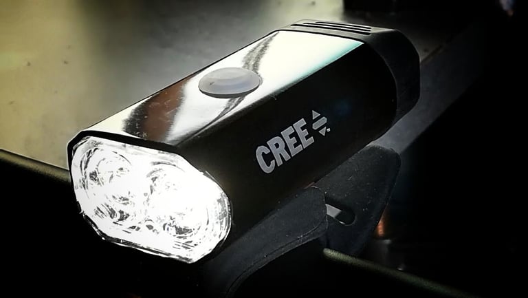 Crane rechargeable front bike light with a Cree LED, clamped to handlebars and switched on.