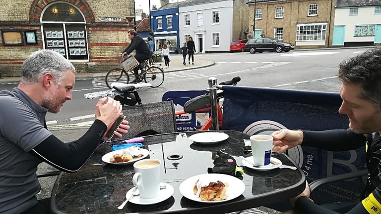 Two riders with coffee and pastries at a pavement cafe table in Framlingham, Suffolk, during the Audax.
