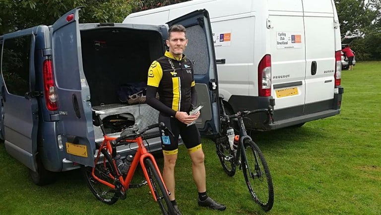 James in cycling kit between two bikes at the open back of a van before the start of the Suffolk Byways Audax.