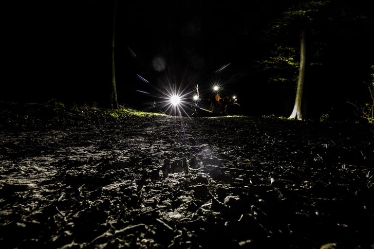 Churned muddy track in the foreground with riders' lights glaring in the dark beyond, Yorkshire True Grit Dark Skies.