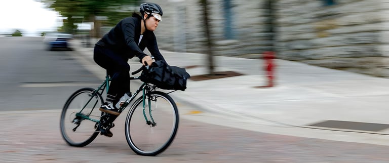 Rider on a green Surly Pack Rat with a front-rack bag, blurred by speed on a city street.