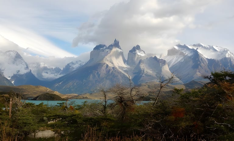 Jagged snow-dusted peaks rise above a lake and autumn scrub in Patagonia, on Andy Lawrence's recent bike trip.