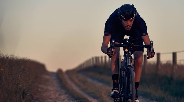 Josh Ibbett rides a Mason bike low over the bars along a grassy farm track at dusk.