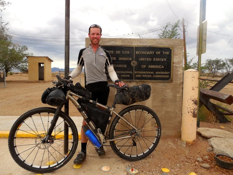 Andy Lawrence with his Enigma titanium hardtail at the US-Mexico border sign at the end of the Tour Divide.