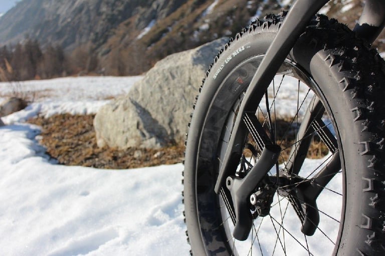 Lauf Carbonara suspension fork on the Travers Bat Fastard, with a 4.8in fat tyre beside a boulder in the snow.