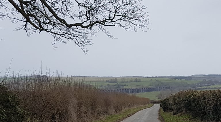 Welland Viaduct seen across fields from a narrow country lane on the Cambridge Pork Pie Run route.