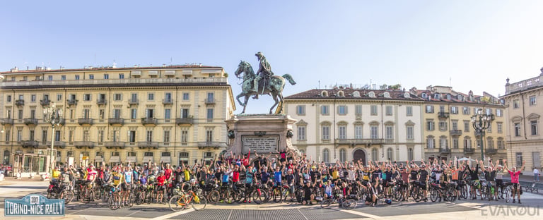 Riders raise their arms at the 2017 Turin Nice Rally start beneath an equestrian statue in a Turin square.