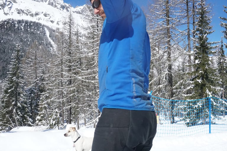 Side view of the Gore Power Trail Primaloft jacket, showing the panelled sides, with a dog and snowy forest behind.