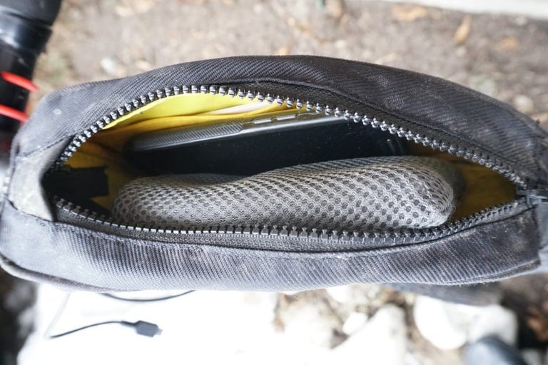 Topeak Fuel Tank unzipped, showing the yellow lining, a mesh pocket and a phone inside.