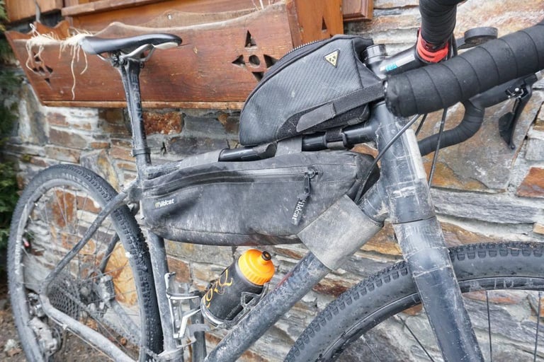 Bikepacking bike with a Topeak Fuel Tank and Wildcat frame bag, leaning against a stone wall.