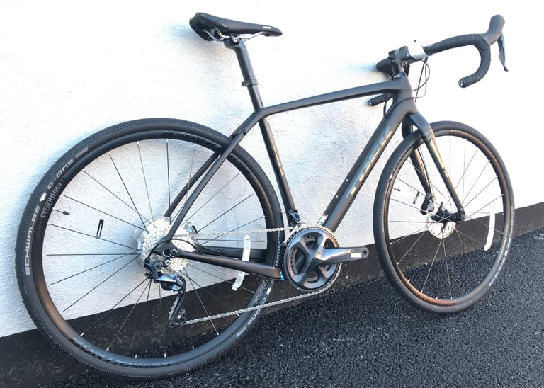 Side view of a black Trek Checkpoint SL carbon gravel bike with Ultegra groupset against a white wall.