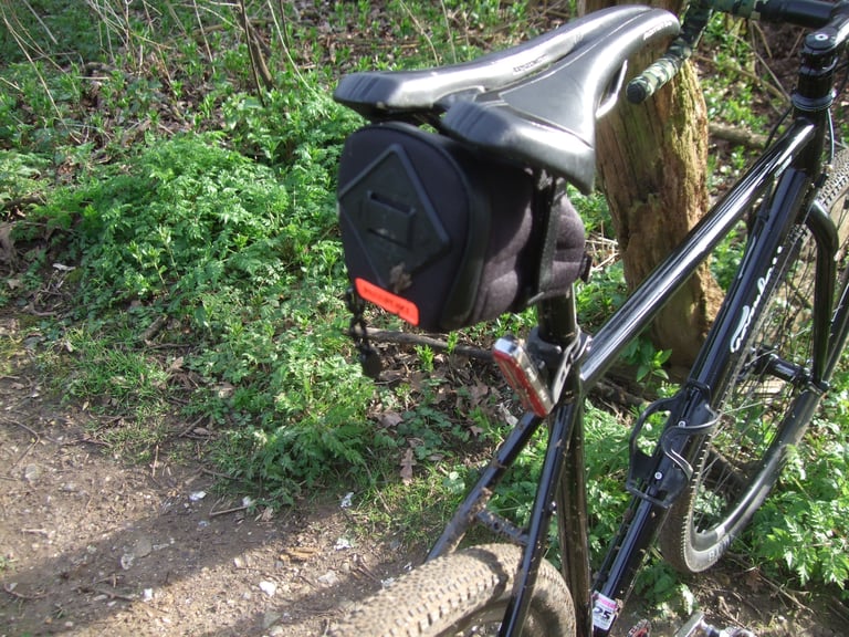 Rear of a Passport Frequent Flyer seat pack with reflective tab and light mount, fitted on a black bike.