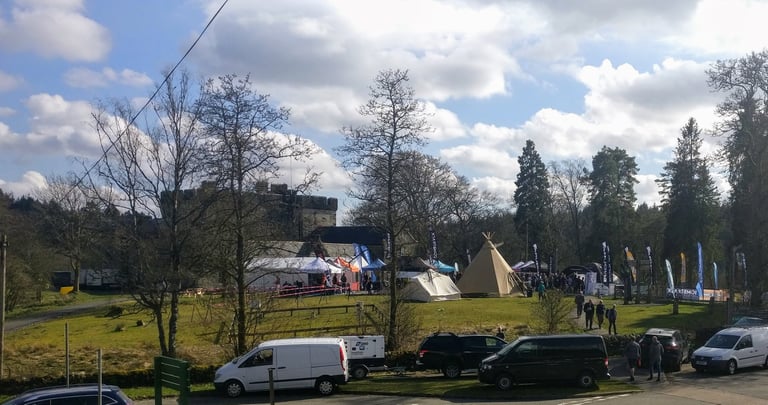 Gravel Expo at Kielder Castle before the Dirty Reiver: a tipi, trade tents and sponsor flags on the lawn below the castle.