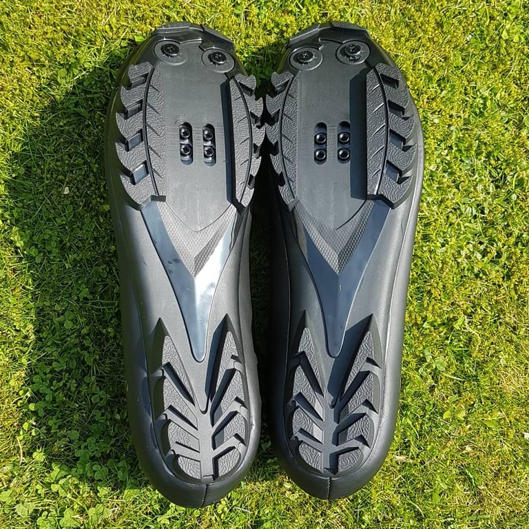 Soles of the dhb Dorica MTB shoes, showing the two-bolt SPD cleat slots and aggressive tread.