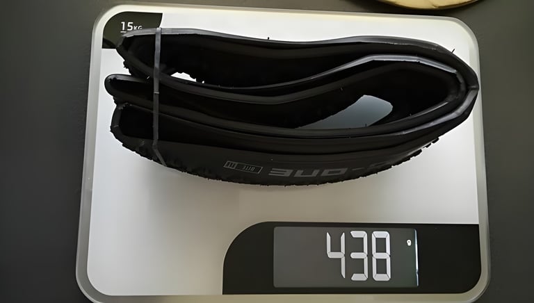 Folded Schwalbe G-One Bite tyre on kitchen scales reading 438 grams.
