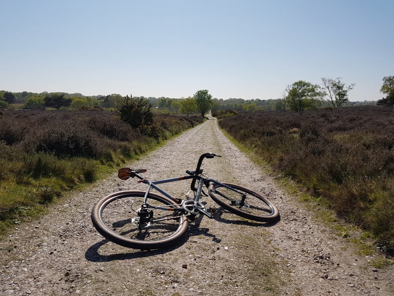Bombtrack Audax lying on a gravel track through heathland on a clear day.