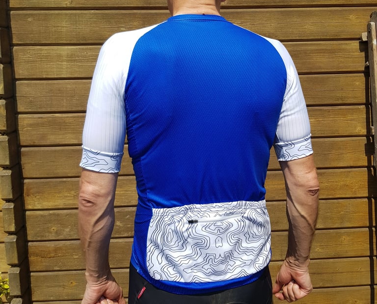 Back of the royal blue Galibier Map Jersey, with a white topographic-print pocket and matching sleeve cuffs.