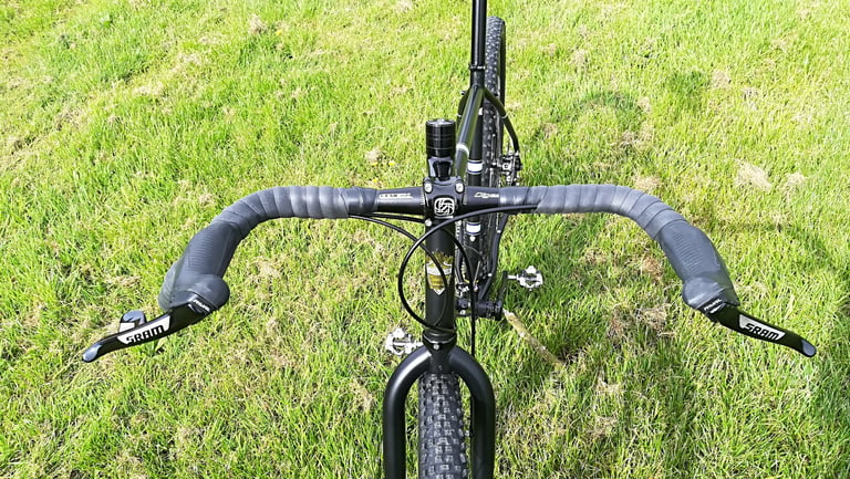 Overhead view of the flared Genetic Digest drop bars and SRAM levers on the Darwin One By MT, over a lawn.