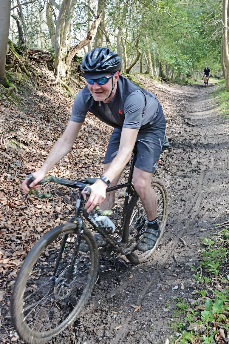 Nigel Leech rides a Fearless Vulture gravel bike down a leafy, muddy woodland descent.