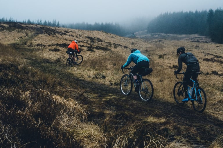 Three riders with bikepacking bags on a misty moorland track during the recon for The Distance.