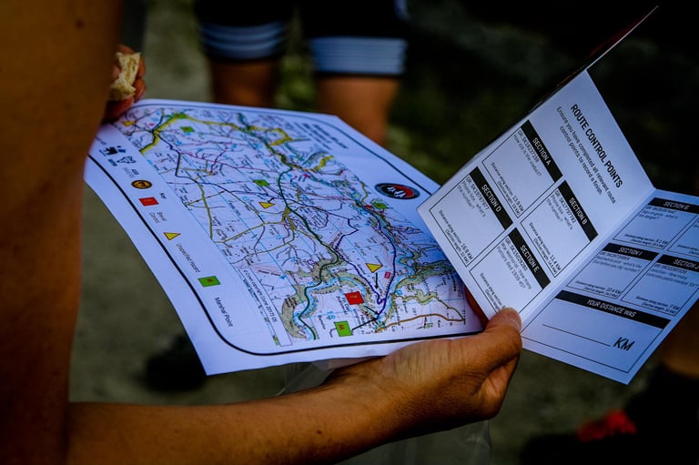 Rider holds the printed route map and brevet card with control points for The Distance bikepacking weekend.