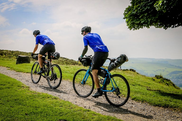Two riders with Passport bikepacking luggage on a gravel track above Peak District fields during The Distance.
