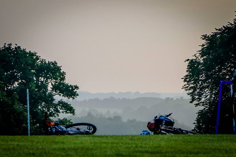 Two loaded bikes lie on the grass at a stop, with misty Derbyshire hills behind.
